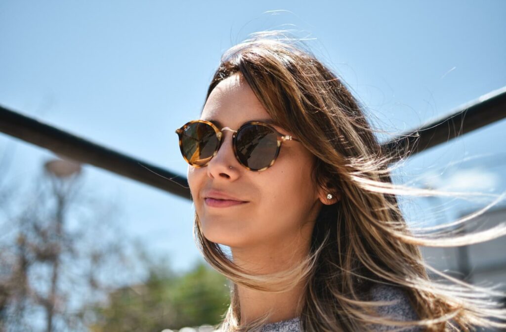 A person wearing stylish sunglasses comfortably waits outside on a sunny day.