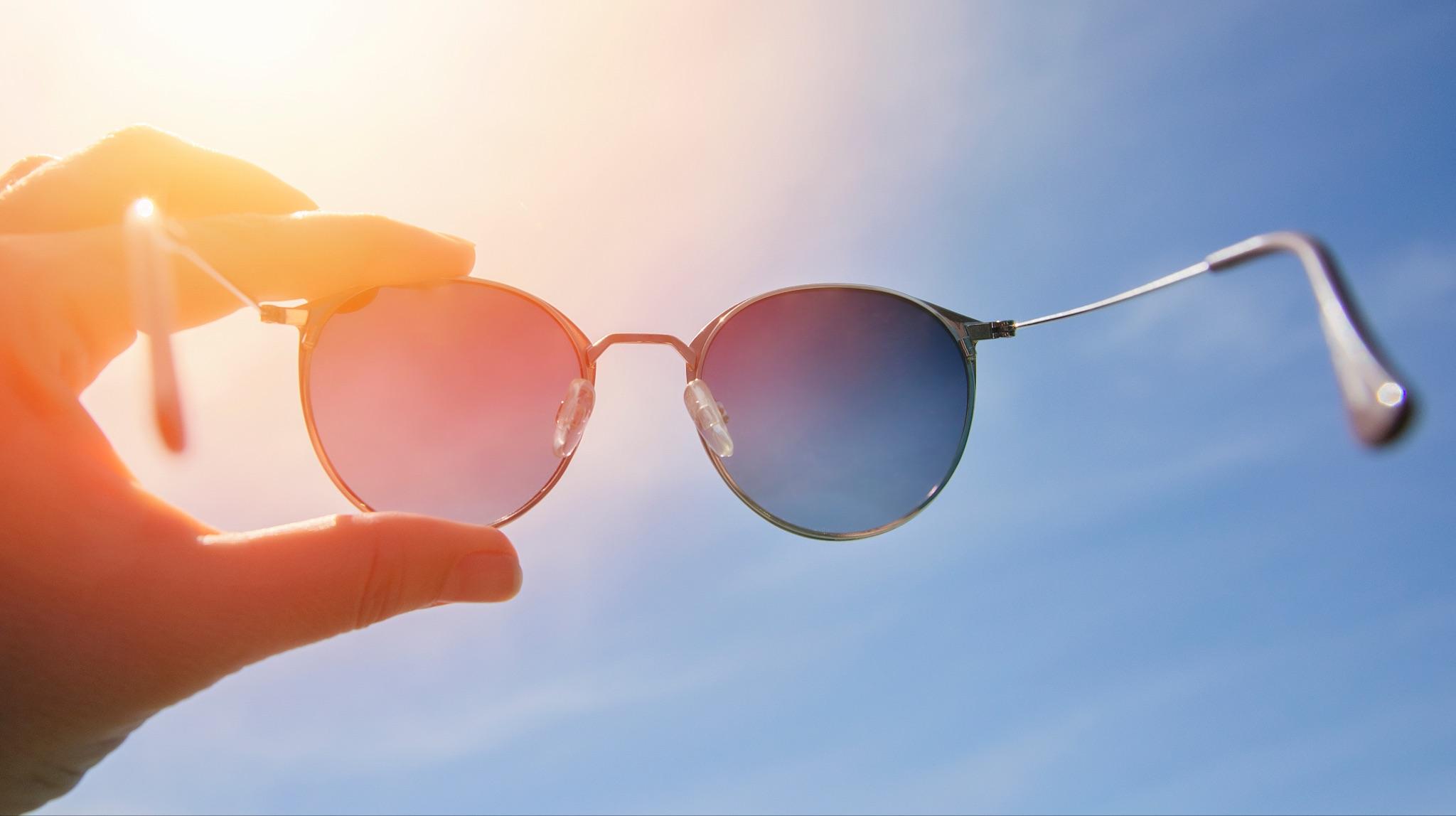Polarized sunglasses held up to the sun to demonstrate glare reduction and lens clarity.